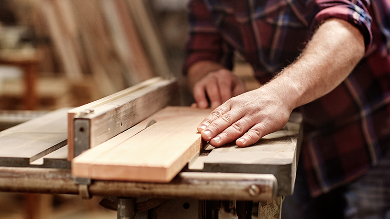 Craftsman cutting a plank of wood for repairs before scheduling home inspection services 